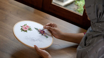 Artistry in Motion: Close-Up of Hand Embroidering a Flower on Fabric with Hoop Stand