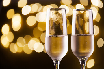 Two New Year's glasses of champagne with highlights on a colored background