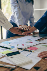 The hands of a team of businessmen joining forces celebrate the concept of unity. A close-up photo...