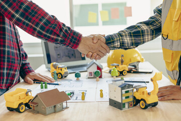 Architect and construction engineer holding hands while working for teamwork and cooperation...