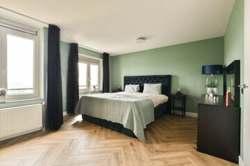 Fototapeta na wymiar a bedroom with green walls and wood flooring in the middle of the room, there is a large bed on the right side