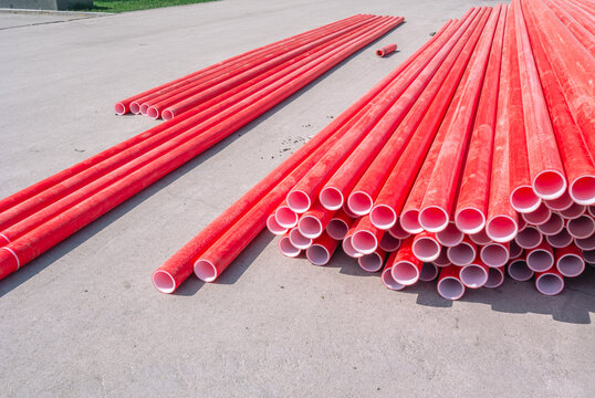 Red polyvinyl chloride pipes for laying electrical cables. Plastic pipe for carrying out communications during construction and repair. Laying pipes in trenches. Background of red long pipes.