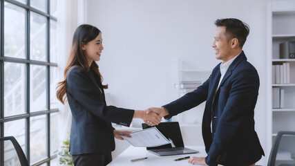 Congratulatory male employer shakes hands with a female job applicant who has been selected for the job.