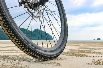 Low angle of a bicycle wheel on the beach, on the sea sand at low tide. The concept of cycling in unusual places. - 668972349