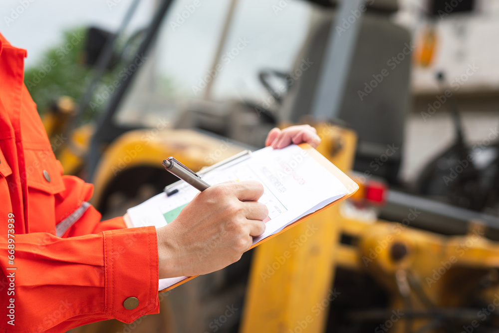 Wall mural a mechanical engineer is using checklist form to verify the excavator or earthmover machine (as back