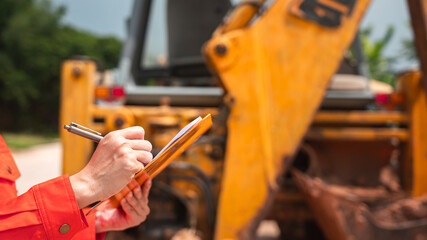 A mechanical engineer is using checklist form to verify the excavator or earthmover machine (as...