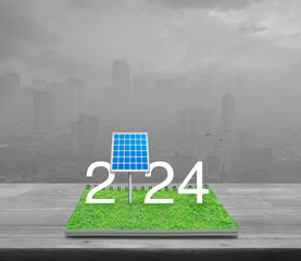 2024 white text with solar cell on green grass on open book on wooden table over pollution city tower and skyscraper, Happy new year 2024 ecological cover concept