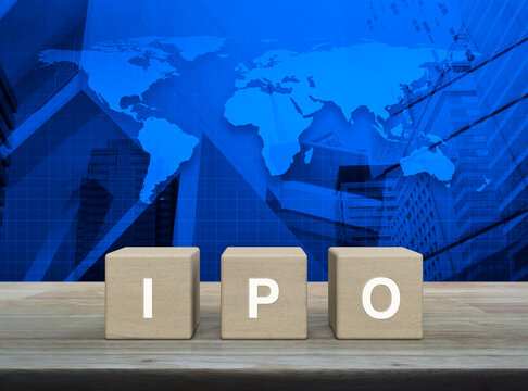 IPO letter on wood block cubes on wooden table over world map, modern office city tower and skyscraper, Initial public offering concept, Elements of this image furnished by NASA