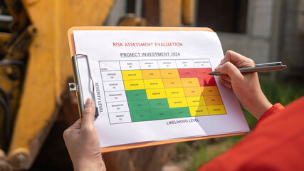 The operation supervisor is using ballpoint pen to marking on the risk assessment matrix form, to...