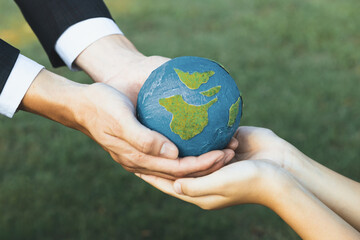 Businessman hand giving Earth globe to little boy as Earth day concept as corporate social...