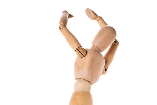 A wooden mannequin holding his hands up in the air. This versatile image can be used to convey concepts such as surrender, victory, celebration, or even a call for help.