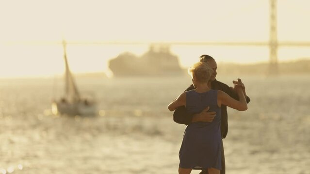 Adult elderly couple dancing near river bridge - big cruise liner ship on background
