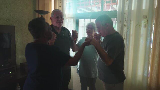 Group of seniors Praying together at home with sunlight shining through window. Four Devouted Elderly People engaged in Prayer holding hands together, HOPE and FAITH