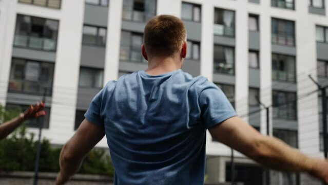 A man and a girl play sports against the background of the windows of a residential complex.