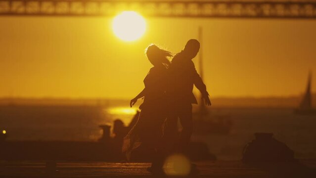Silhouetted couple sharing a moment - dancing and hugging on sunset or sunrise