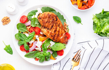 Healthy salad with grilled paprika and chicken, feta cheese, cherry tomatoes, walnut, red onion and lettuce, white table background, top view