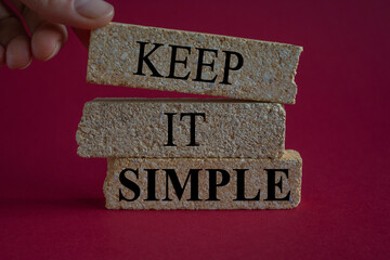 Keep it simple symbol. Concept word Keep it simple on beautiful brick blocks. Businessman hand. Beautiful red background. Business motivational keep it simple concept. Copy space.