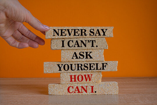 Motivational and Inspirational quotes -Never say i can't. Ask yourself how can i. Words on brick blocks. Beautiful orange background. Businessman hand. Business and self development quote concept