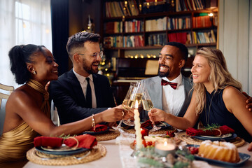 Multiracial group of cheerful friends having fun while toasting at dining table on New Year's Eve.