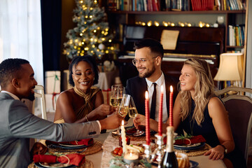 Happy people celebrating Christmas and toasting with champagne during dinner at dining table.