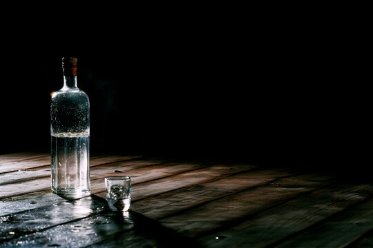An alcohol kills. An empty alcohol bottle on a table on a dark background. The concept of alcohol dependence. An empty alcohol bottle on the table 