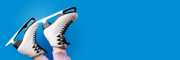 ice skates on feet on blue background, figure skating shoes, winter sports, seasonal fun, banner