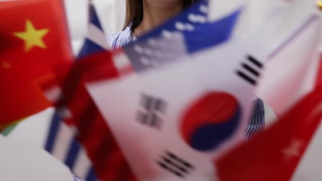 Woman holding different flags in her hands, global unity, international event, diverse cultures, multi-national celebration, international diversity