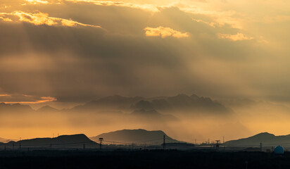 The rays of the sun break through the clouds, mountains in the fog after the rain in the background