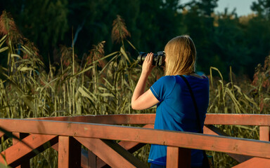 Turystka stoi na drewnianym moście i robi zdjęcia aparatem fotograficznym