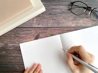デスクでノートに字を書く女性の手元