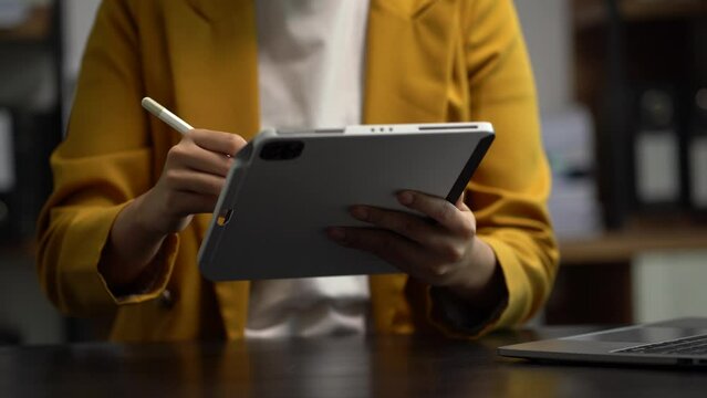 Women are using tablet and laptop to work at the desk in the morning.