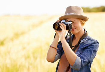 Woman, camera and photography with safari, vacation and holiday with wheat field and plants. Nature, photographer and outdoor with traveler blog and countryside with photo for adventure and journey