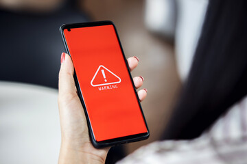 woman using smartphone with warning triangle showing a system error. Concepts of system...