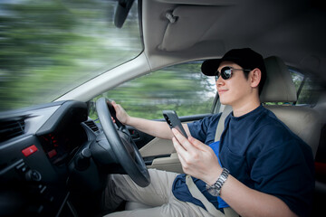 Naklejka premium Asian man on vacation smiles happily holding a smartphone to open online map to find new route while heading to a vacation destination. concept of traveling to find inspiration and safety in traveling