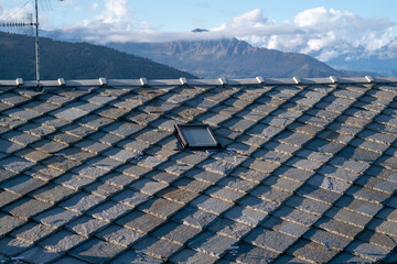 roof with stone tiles, typical of mountain house houses, blue gray granite stones, mountains in...