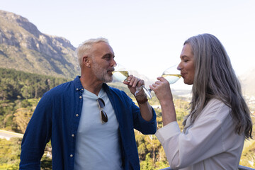 Happy senior caucasian couple drinking wine on balcony