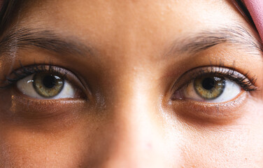 Portrait of biracial casual businesswoman with hijab and green eyes in creative office