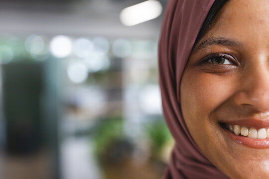 Portrait of happy biracial casual businesswoman with hijab in creative office, copy space