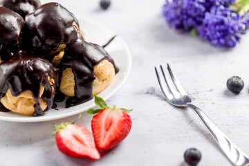 Profitrolls decorated with chocolate on a light background