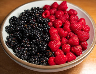 Summer berries, raspberries, blackberries. Dessert on a white plate. Vitamins, healthy nutrition. Fresh raspberries and blackberries on plate lined with symbol of yin and yang
