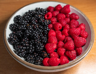 Summer berries, raspberries, blackberries. Dessert on a white plate. Vitamins, healthy nutrition. Fresh raspberries and blackberries on plate lined with symbol of yin and yang