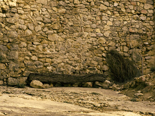 poutre installée en banc adossée à un mur en pierre en provence avec fagot de bois sur le côté