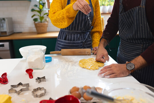 Midsection of caucasian couple preparing dough for christmas cookies in kitchen, copy space