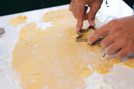 Hands of caucasian man cutting star shapes in cookie dough, copy space