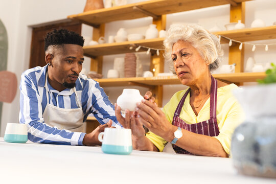 Two diverse female and male potters discussing about job in pottery studio