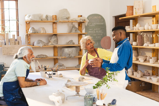 Happy diverse group of potters discussing in pottery studio