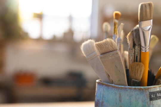 Close up of pottery brushes in clay cups in pottery studio