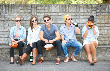 Fototapeta premium Social, portrait and friends on a bench in public for drinks, conversation and bonding on the weekend. Happy, group and people in the city for alcohol, communication and together for society