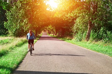 Young Woman Explores the Countryside. Scenic Cycling. Back View of a Carefree Woman on a Bicycle