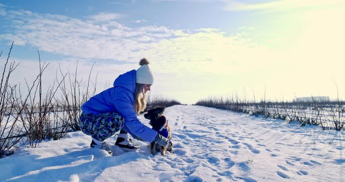 A girl positions her dog for a photo in a winter landscape.
